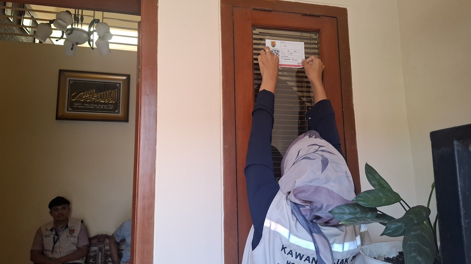 Petugas pajak memasang stiker IQRO di salah satu wajib pajak, baru-baru ini.
