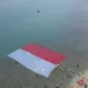Sejumlah penyelam gabungan membentangkan bendera Merah Putih di perairan laut Merak, Kota Cilegon, Banten.